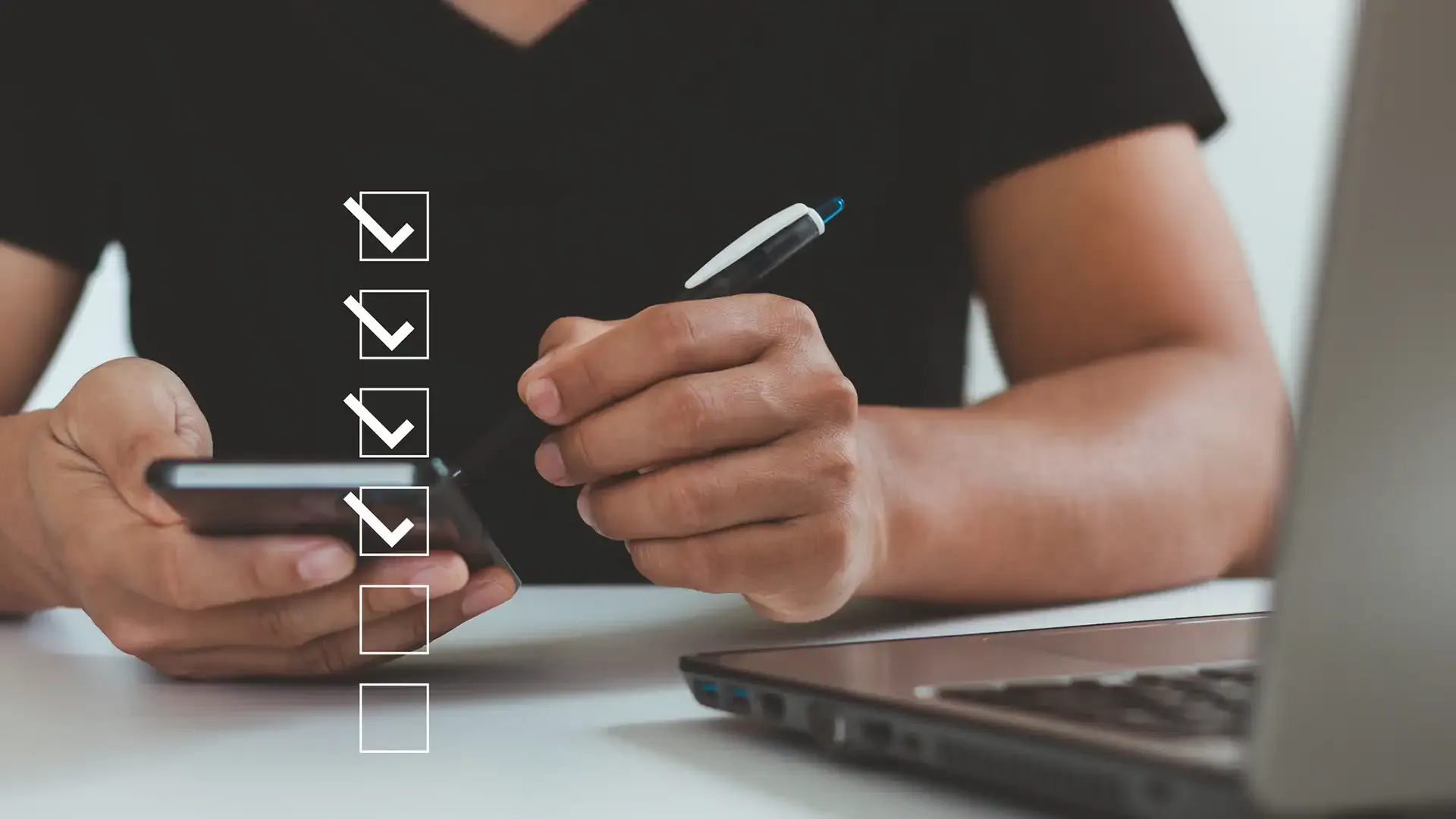 A man running a series of checks using a phone and a laptop